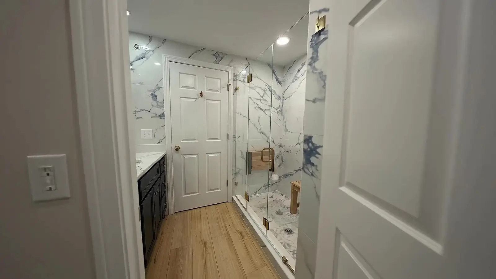 Finished bathroom with blue-veined marble-look tile and a glass shower by Apex Tile and Services