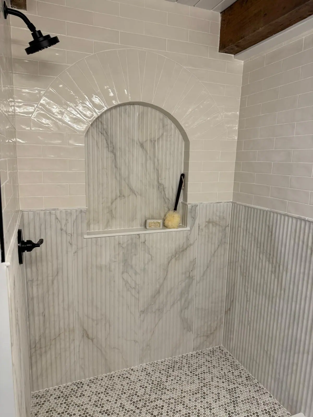 Shower with an arched marble-look niche, fluted lower wall tile and white glossy tile above