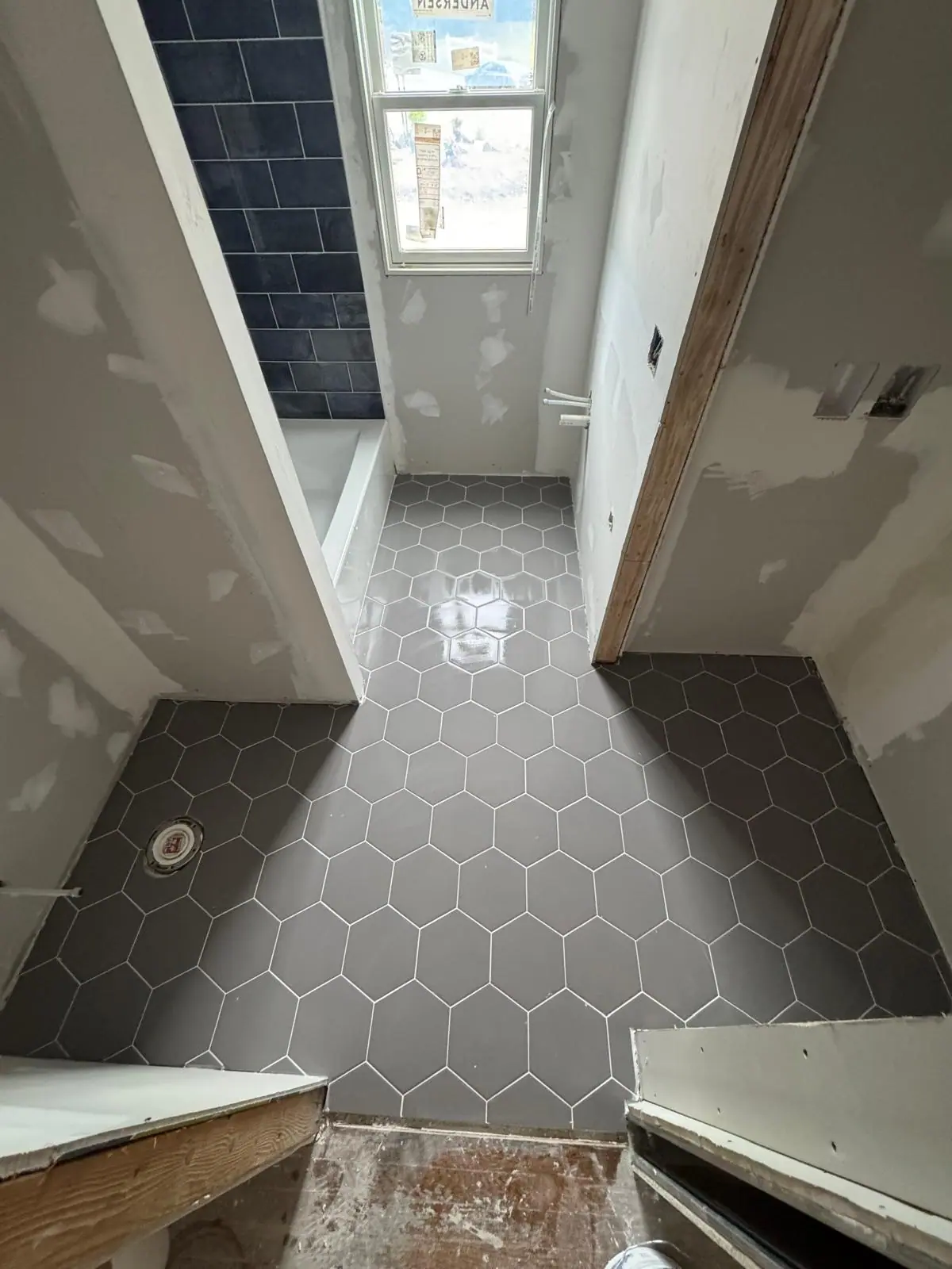 Charcoal hexagon tile bathroom floor installed before the walls are finished