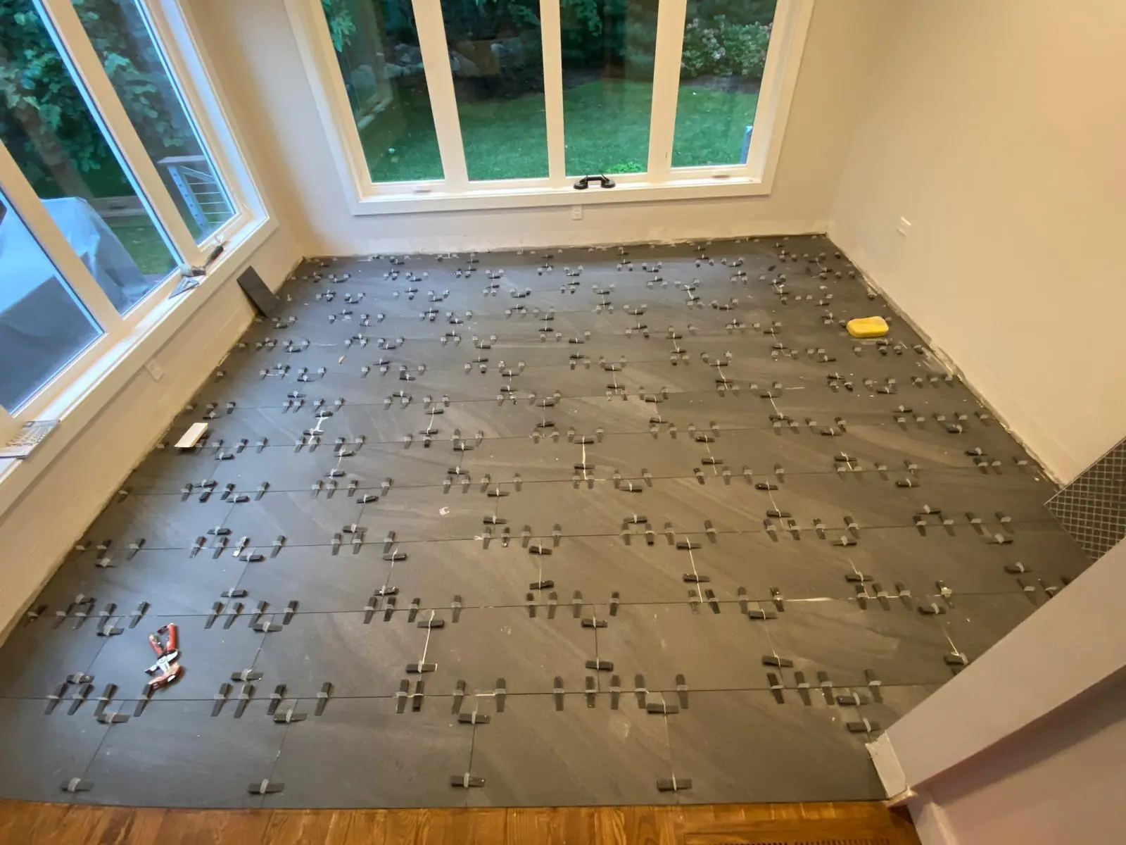 Large gray floor tiles set with leveling clips during installation