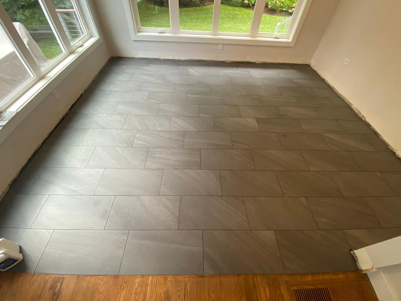 Finished large-format gray porcelain floor in a bright room with windows