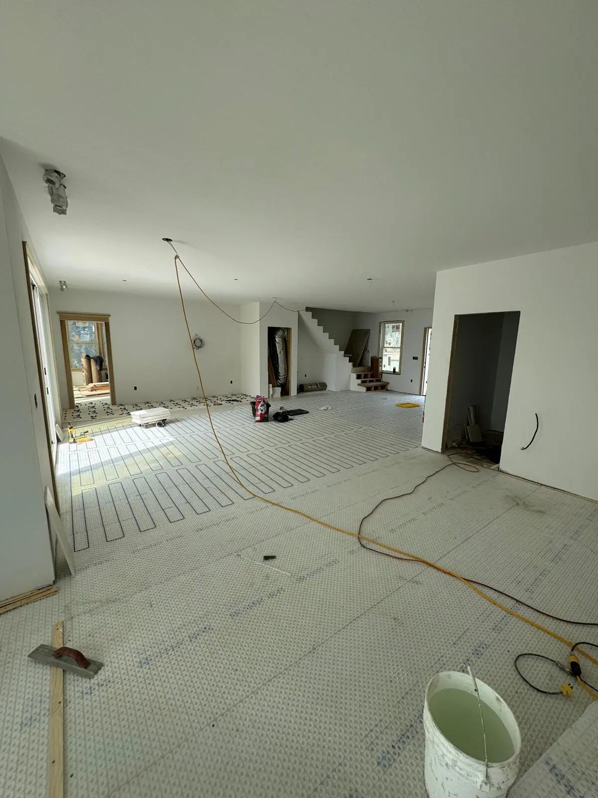 Radiant heating cable laid across a large open-plan floor before tiling