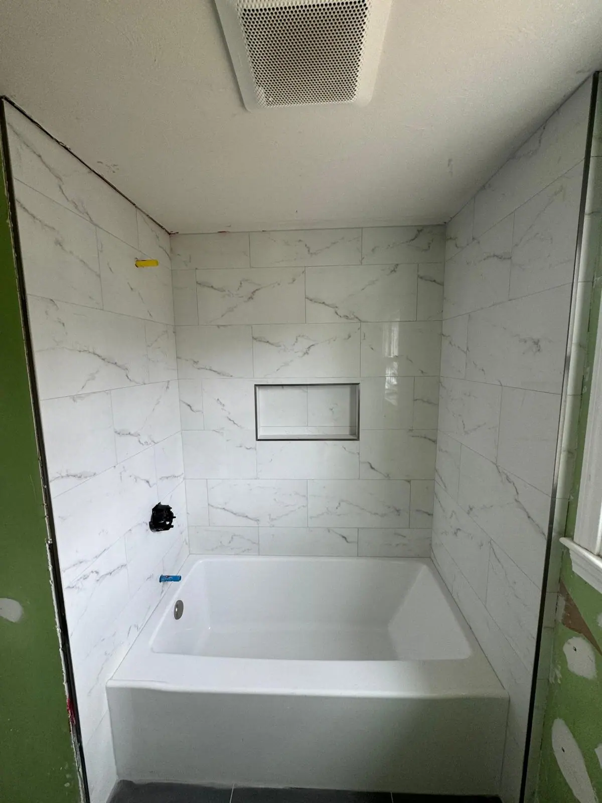 Tub surround in large marble-look tile with a recessed niche