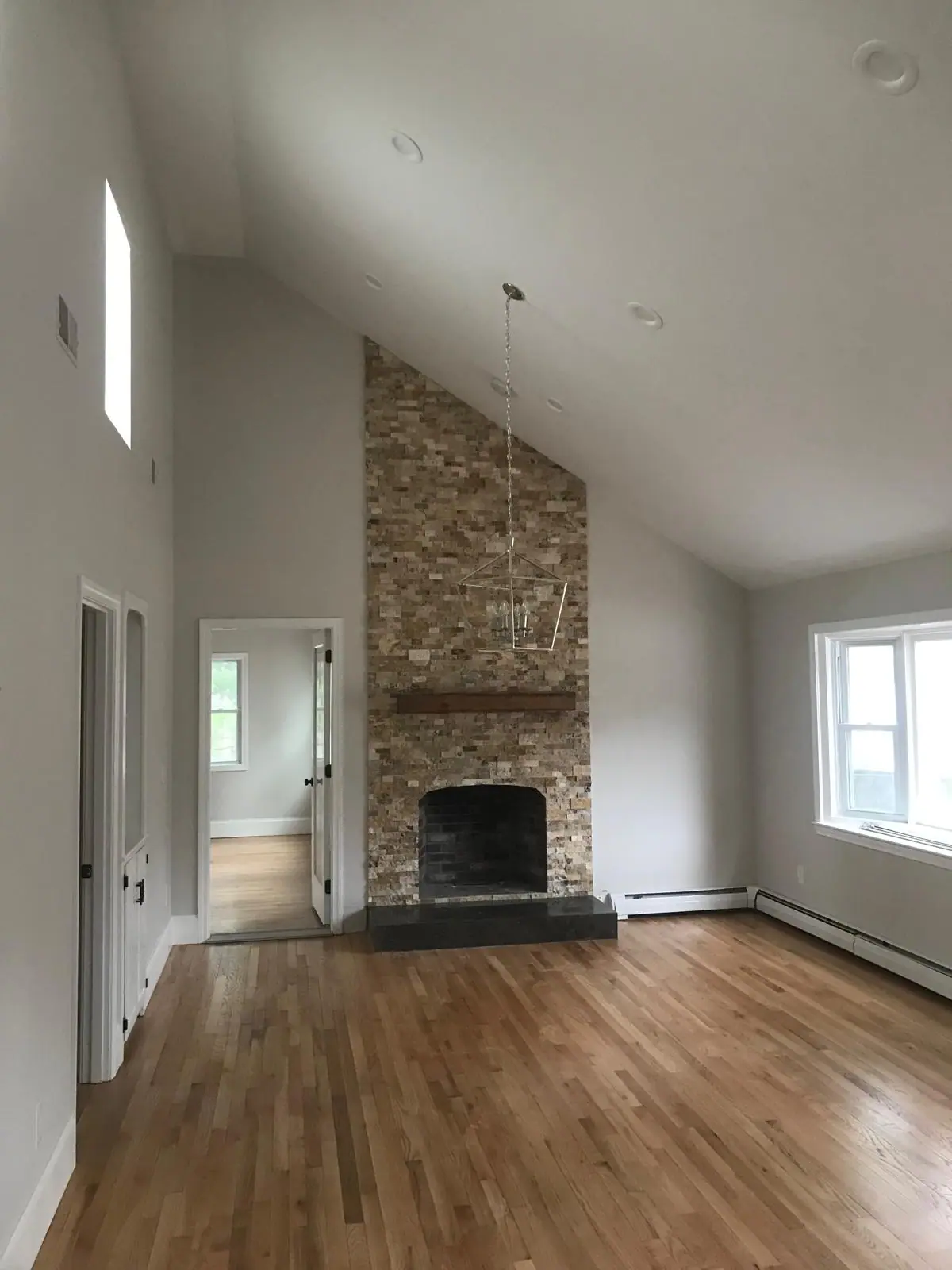 Floor-to-ceiling stacked stone fireplace in warm tones under a vaulted ceiling, with a wood mantel and a dark hearth