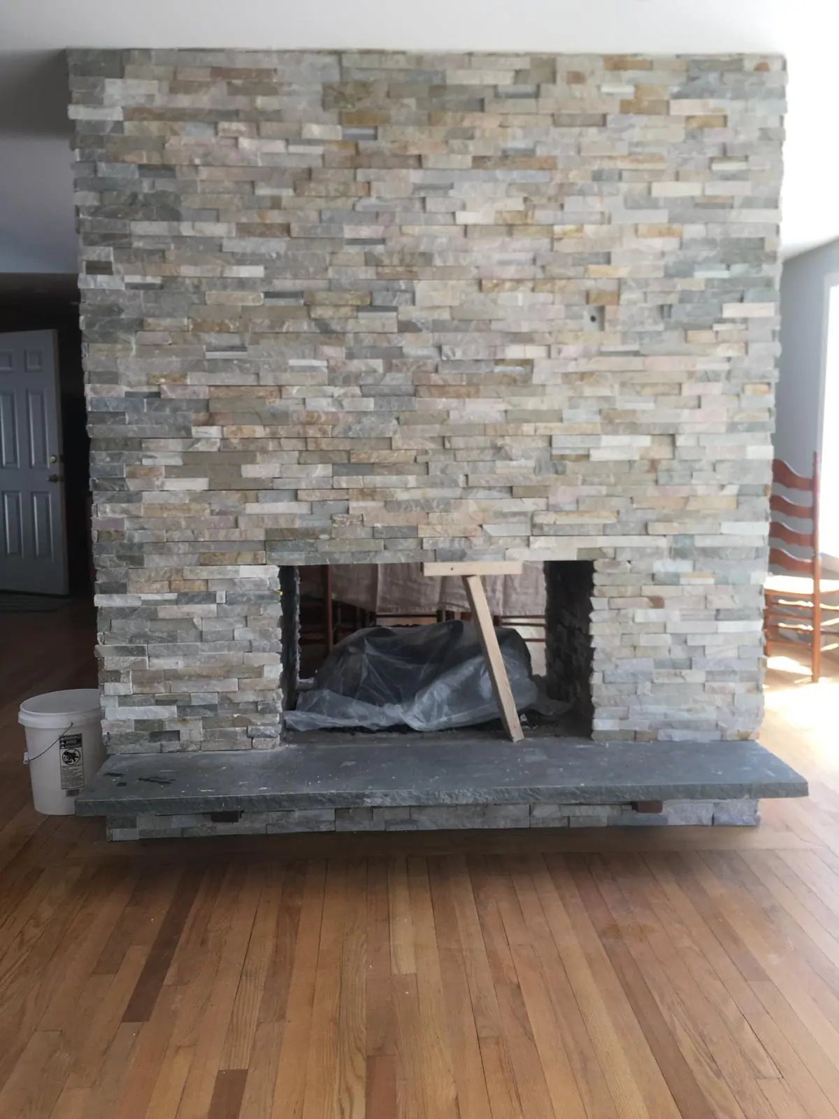 Two-sided fireplace clad in natural stacked stone veneer with a thick bluestone hearth, just after installation
